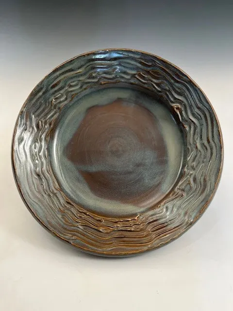 Wide-rimmed plate with carved wavy texture in blue-green and rust