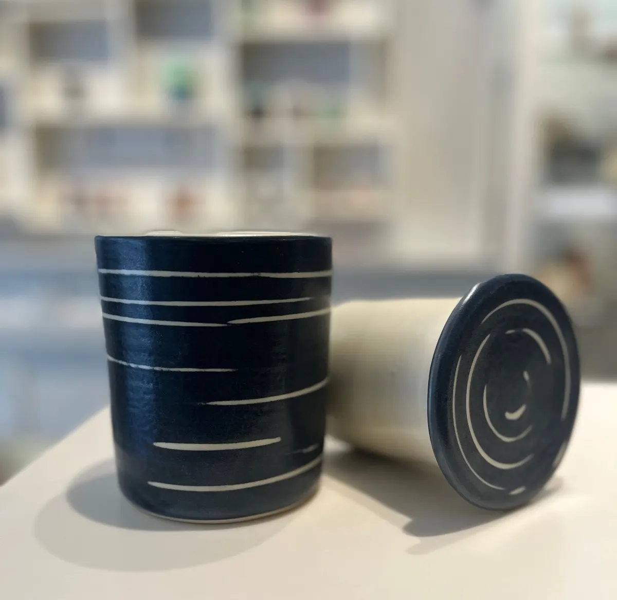 Navy lidded jar with white horizontal brushwork, lid resting alongside