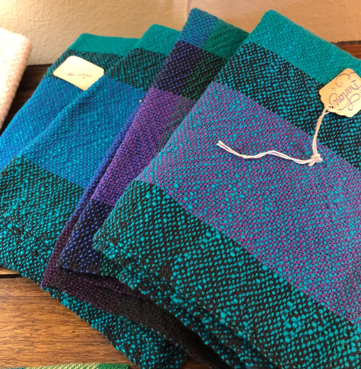 Stack of handwoven scarves in teal, purple and black
