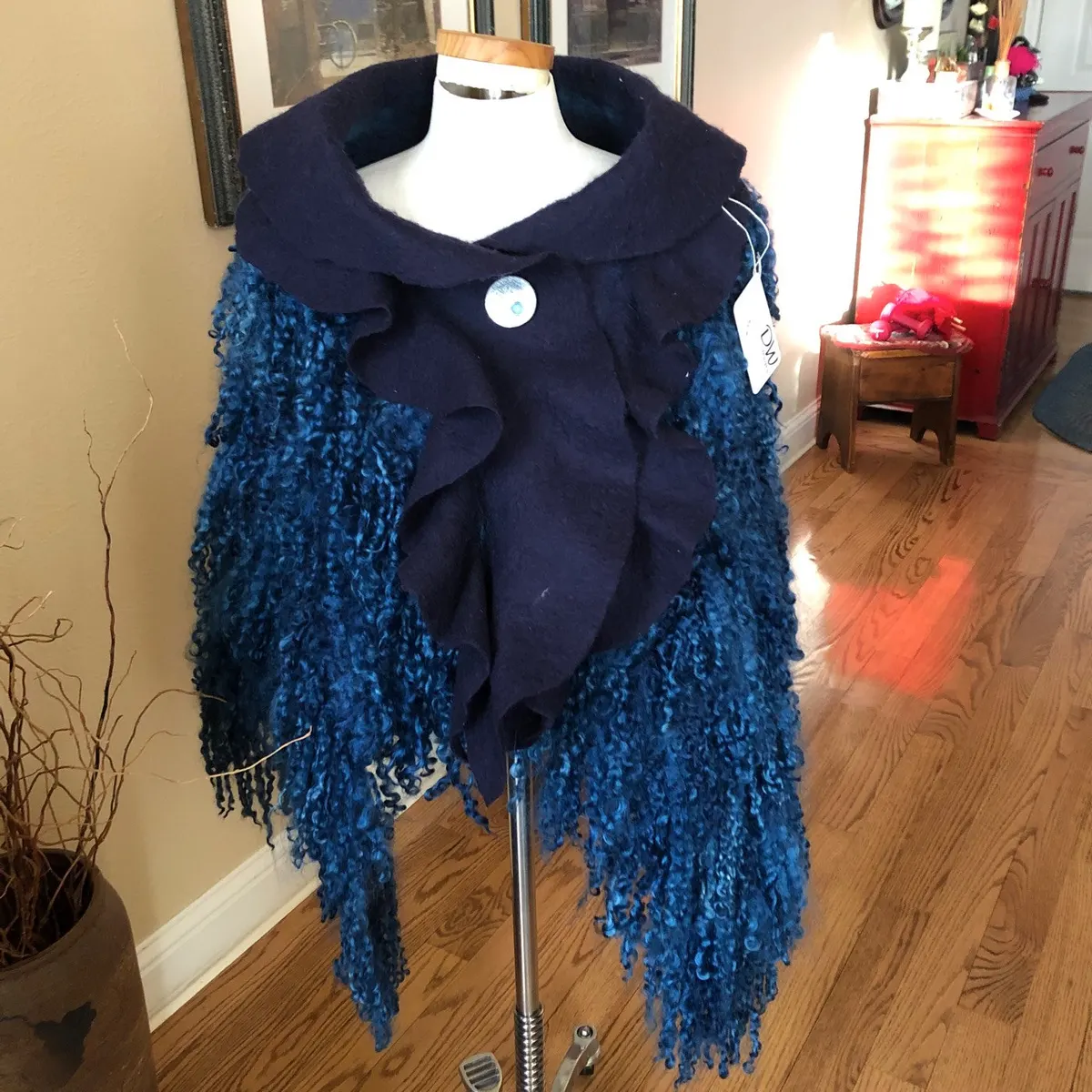Navy knitted shawl with a wide collar and long fringe on a dress form