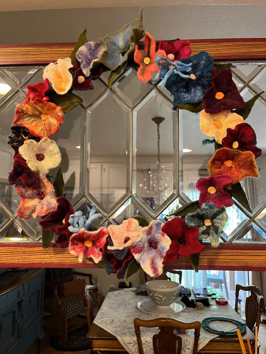Wreath of felted flowers in coral, burgundy and blue on a mirror