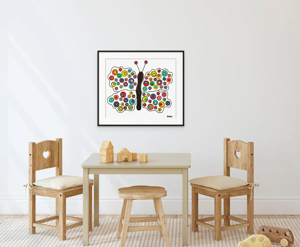 Framed butterfly artwork in bright dots above a child's table and chairs