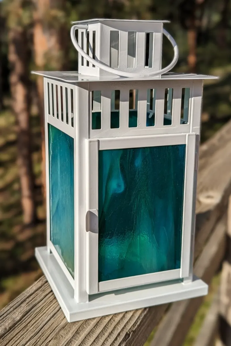White metal lantern fitted with teal fused glass panels