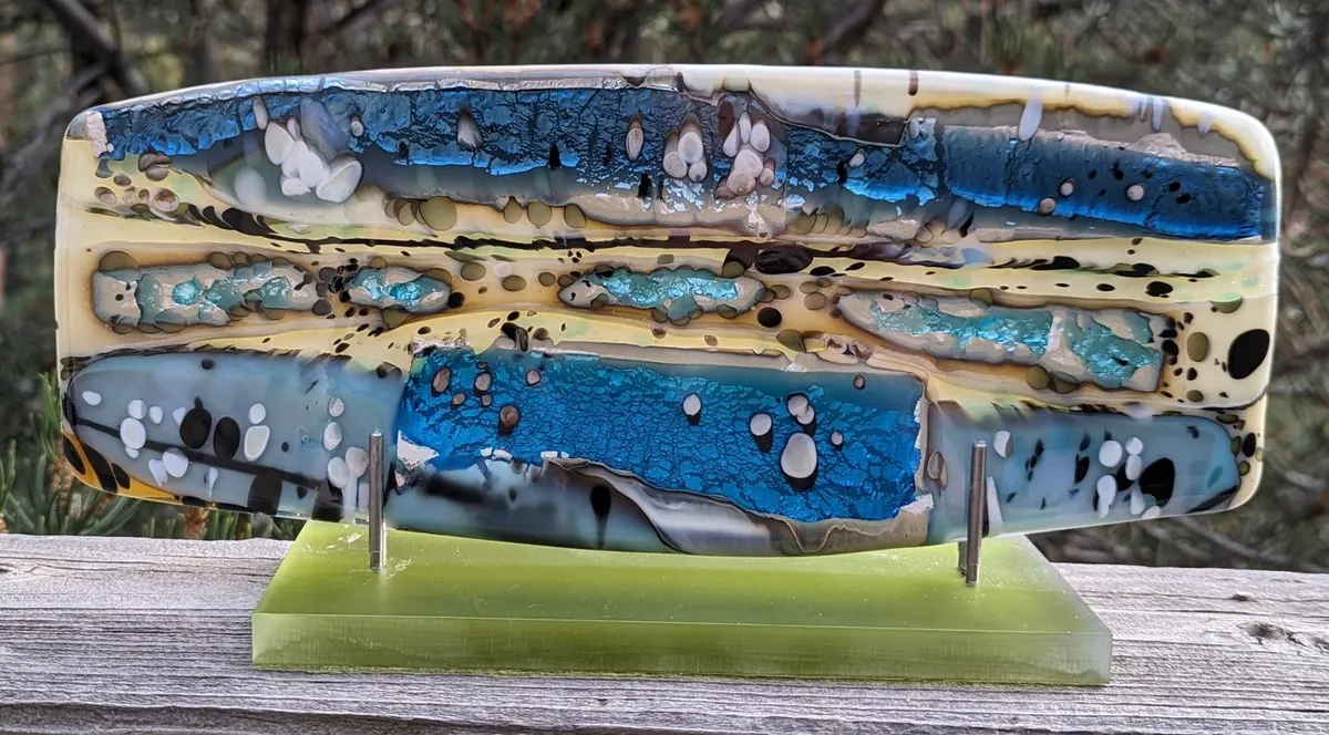 Long low fused glass panel in blue, cream and grey on a green base