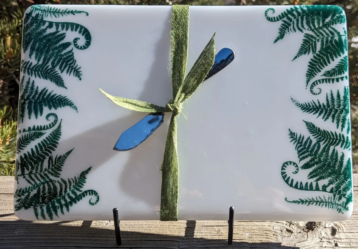 White fused glass tray with green ferns and a ribbon-tied dragonfly