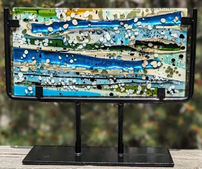 Rectangular fused glass panel in blue and green bands on a black stand