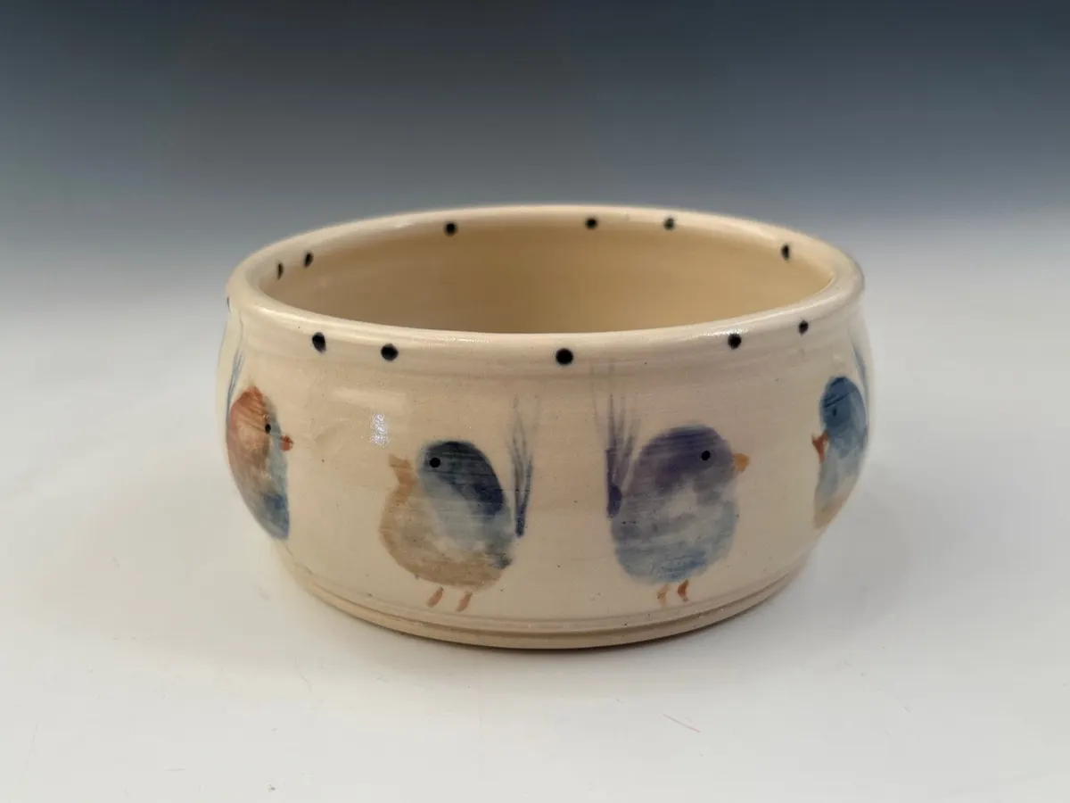 Small cream bowl painted with blue birds and a dotted rim
