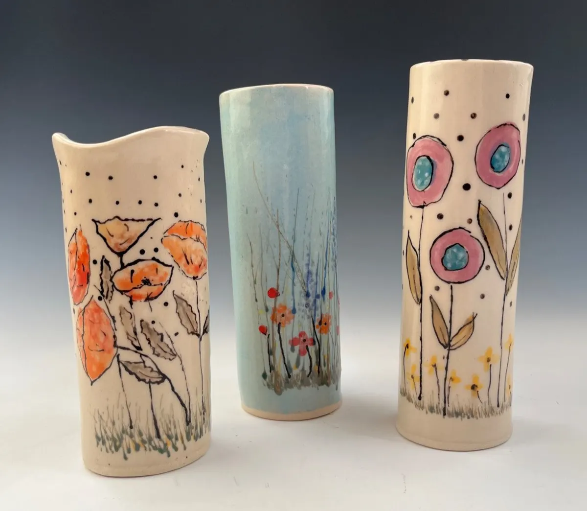 Three cylinder vases painted with poppies, grasses and round blossoms