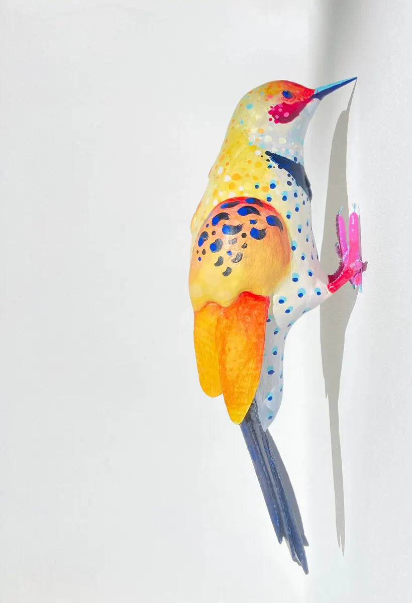 Small painted bird sculpture in yellow and blue