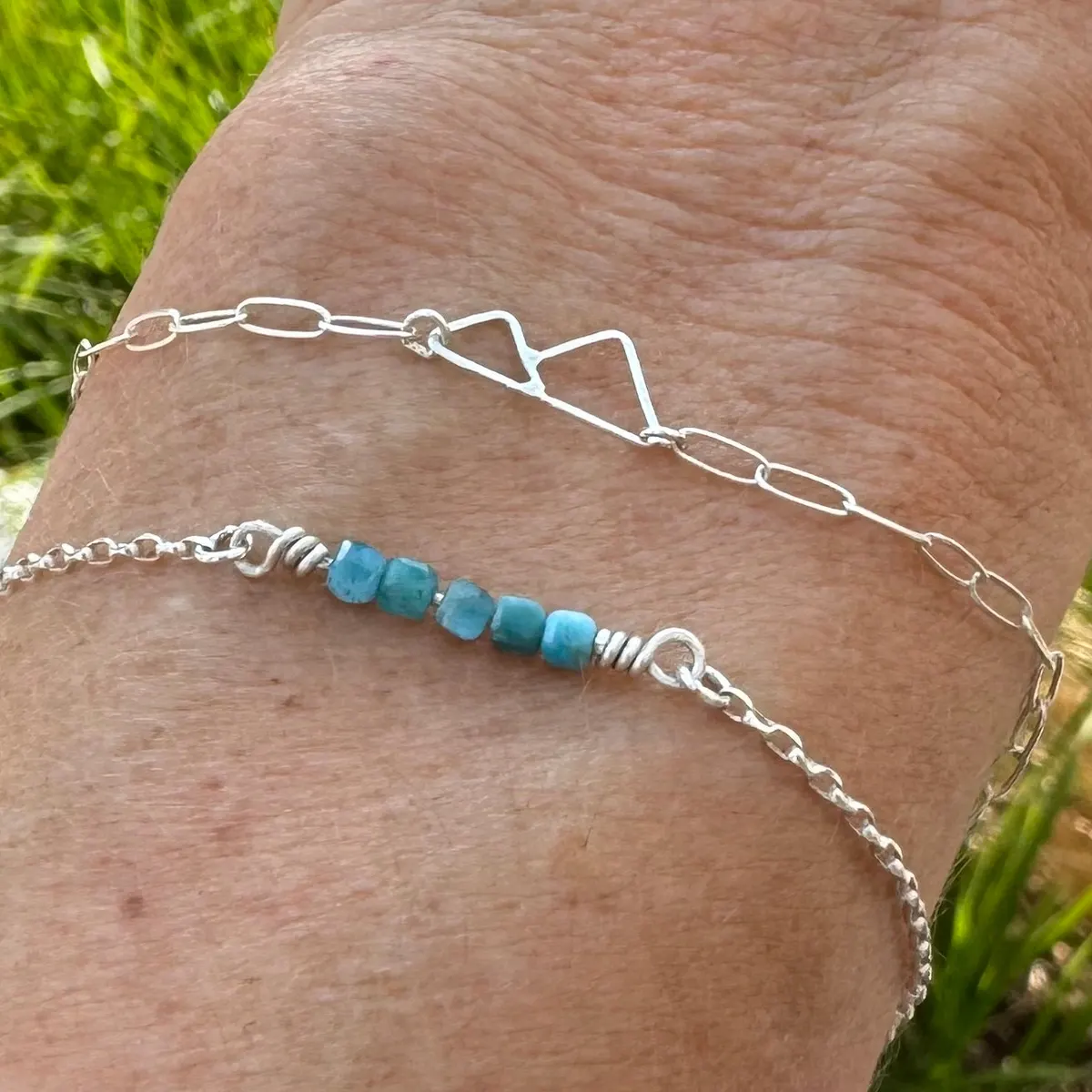 Two fine silver bracelets, one with pale blue beads, worn on a wrist
