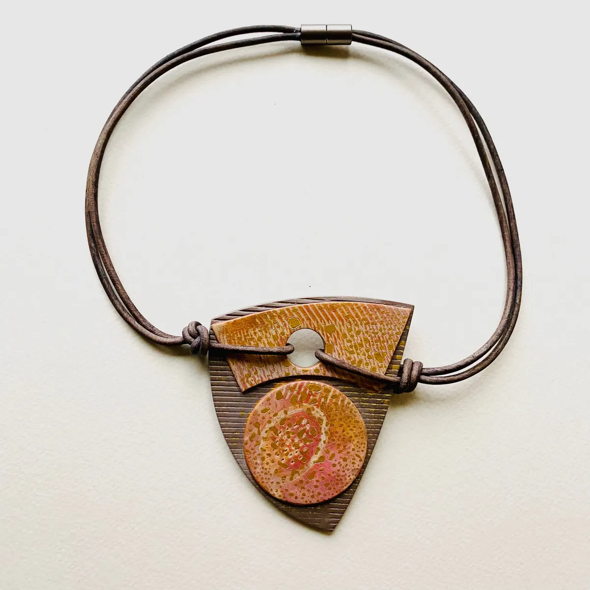 Triangular polymer clay pendant in warm ochre on a brown leather cord