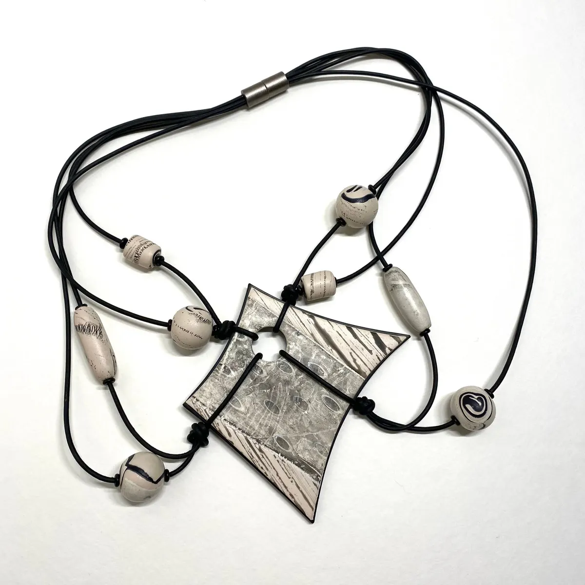 Angular black and white polymer clay pendant on multi-strand black cords