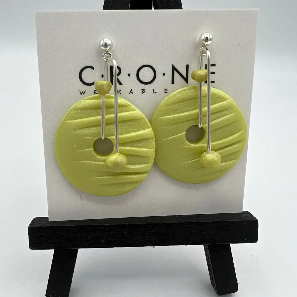 Round chartreuse polymer clay drop earrings on a display stand