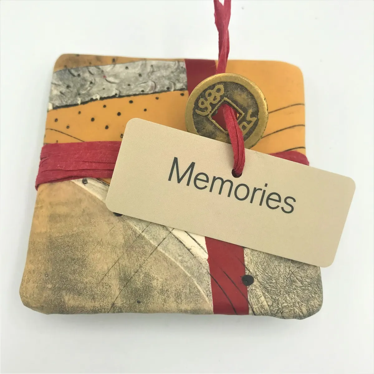 Polymer clay wall piece in muted greys and red with a Memories tag