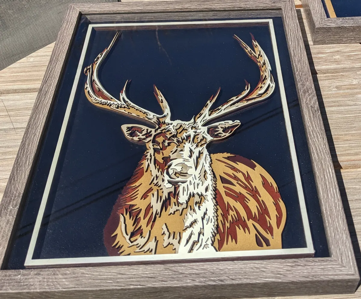 Layered laser-cut elk portrait in cream and rust, framed in weathered wood