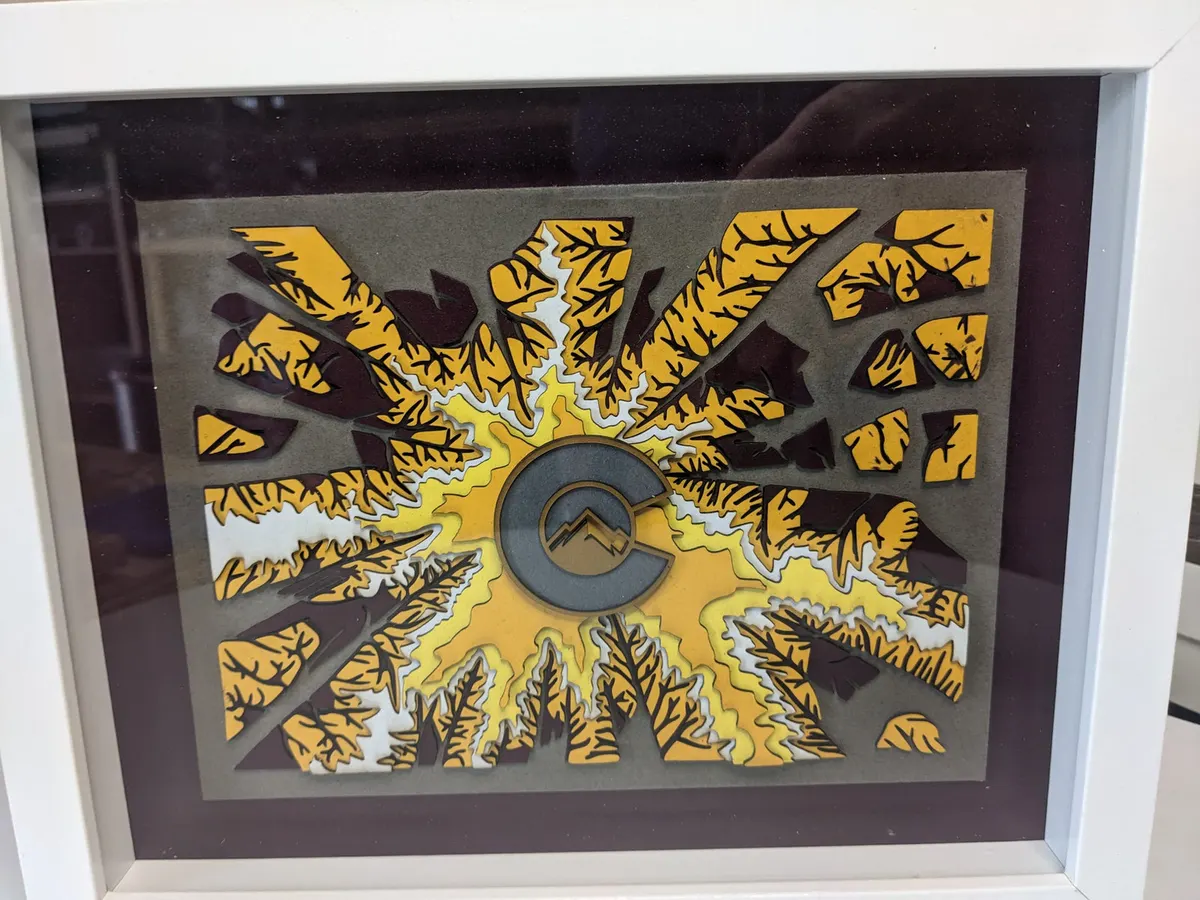 Layered laser-cut Colorado flag motif set in a radiating forest design