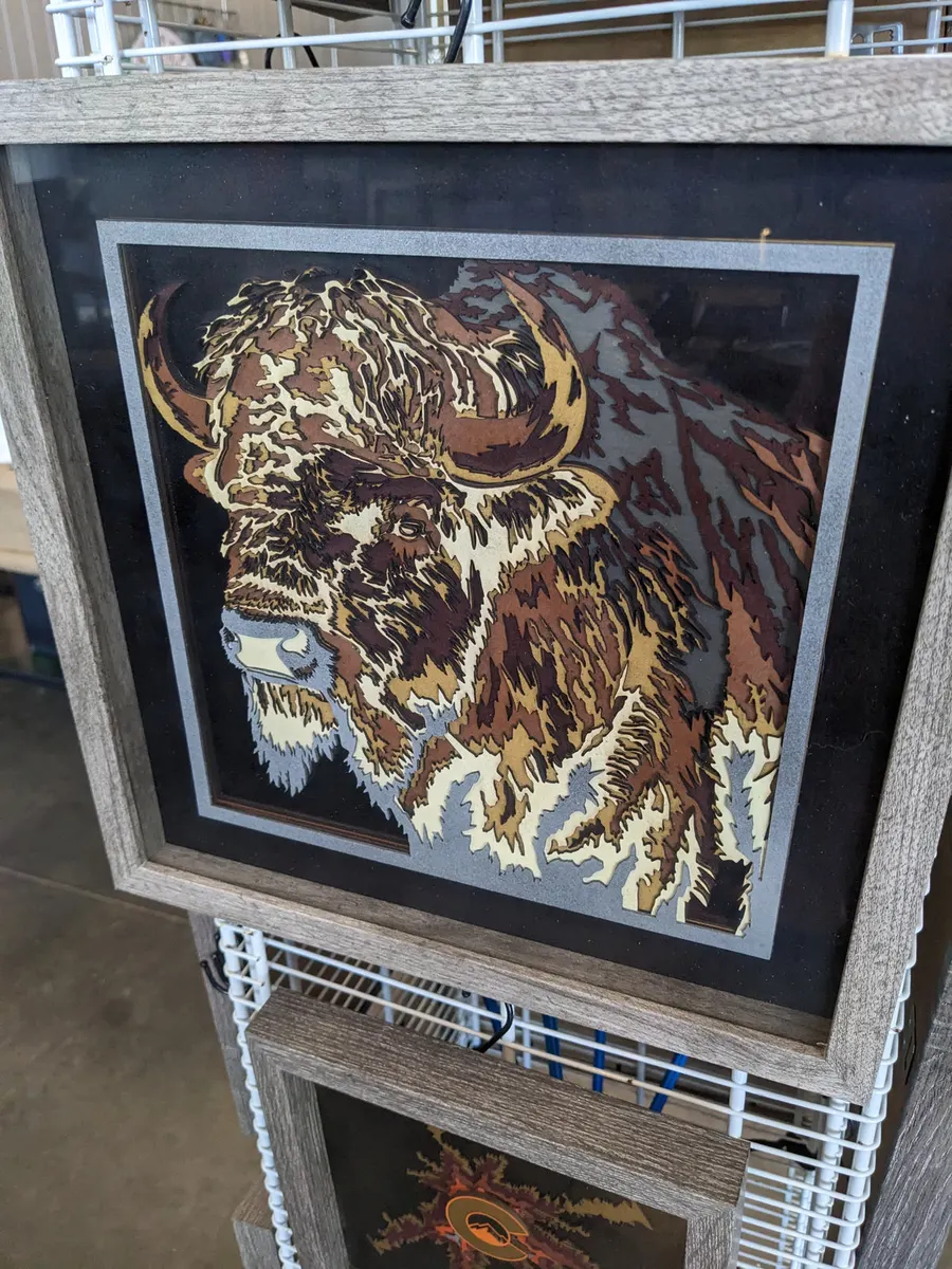 Layered laser-cut bison portrait in gold and brown, framed in wood