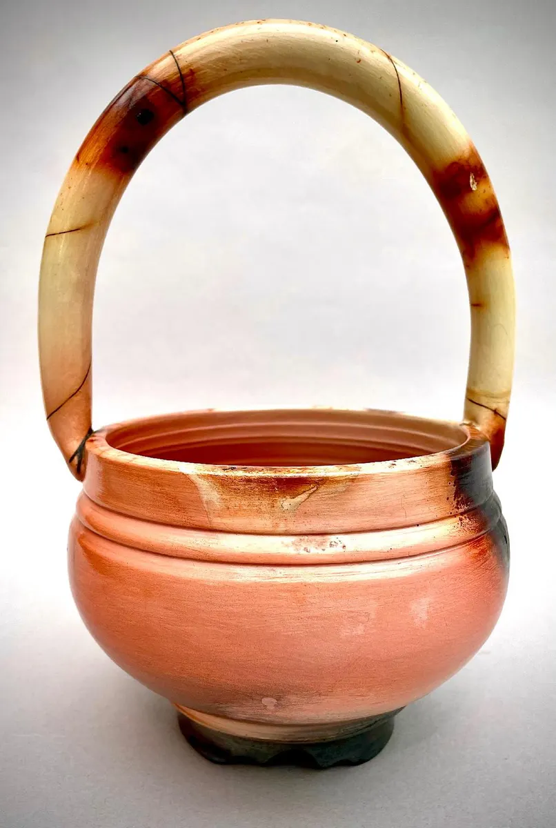 Round handled basket form in cream and amber with a high arched handle