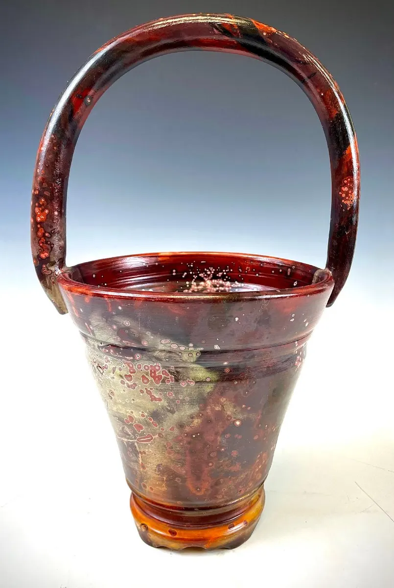 Handled basket form in deep red and amber with a high arched handle