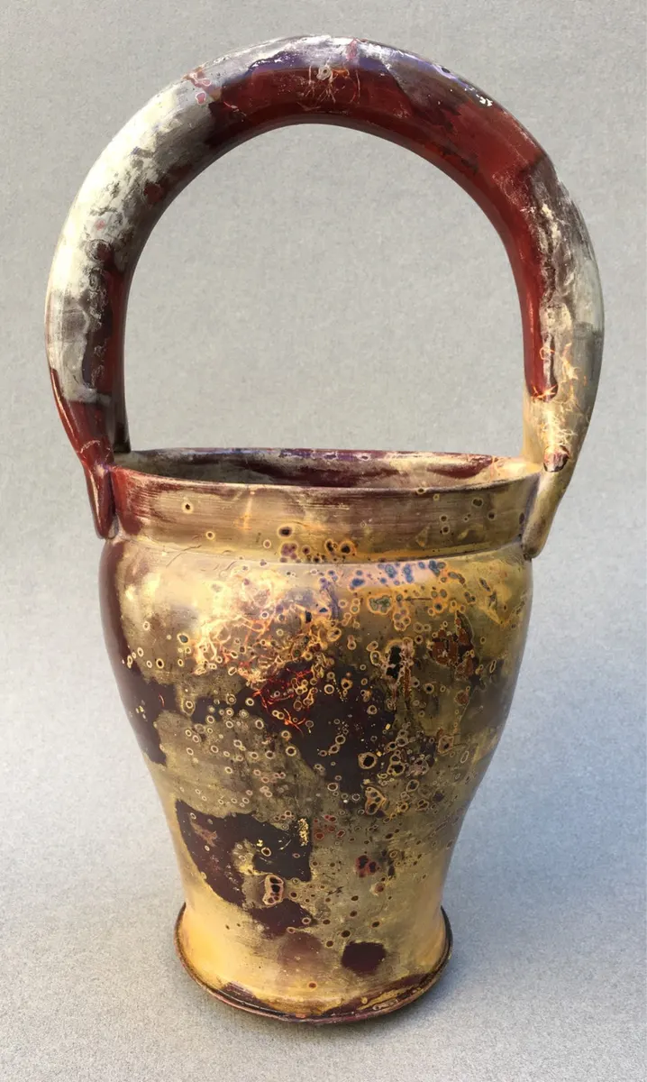 Handled basket form in cream and dark red with a high arched handle