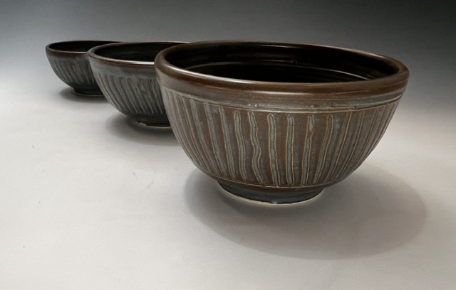 Three nested ribbed stoneware bowls in olive-brown glaze